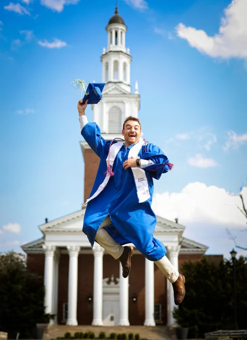 Photo of graduate in cap and gown in front of Memorial Hall