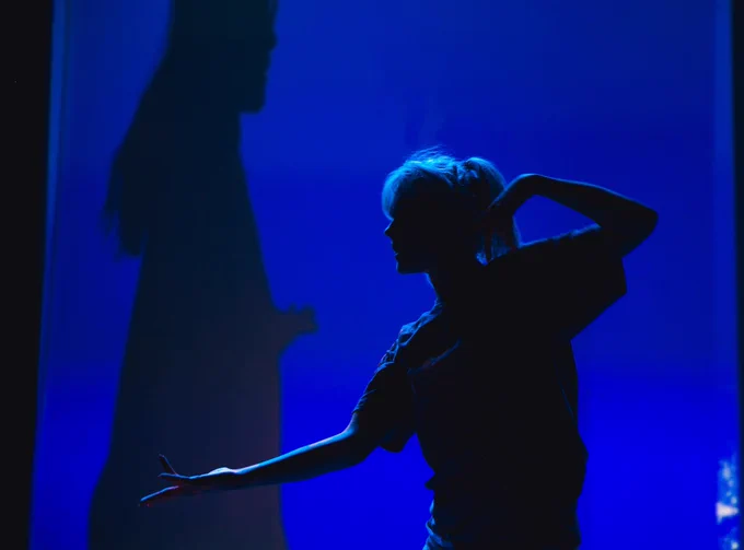 Alice backlit dancing with a projected shadow behind her