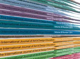 a stack of previous issues of the International Journal of Art and Design Education (IJADE) in green, yellow, blue and lilac