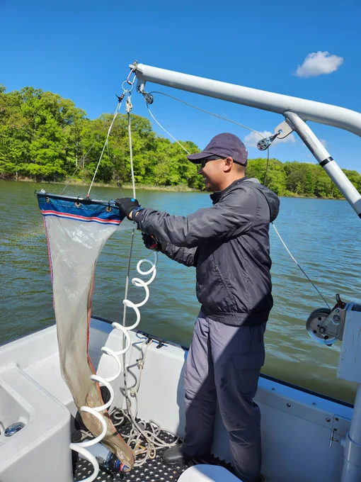 This photo shows Clinton (research technician) handling a plankton tow net on a small boat in the Rhode River.
