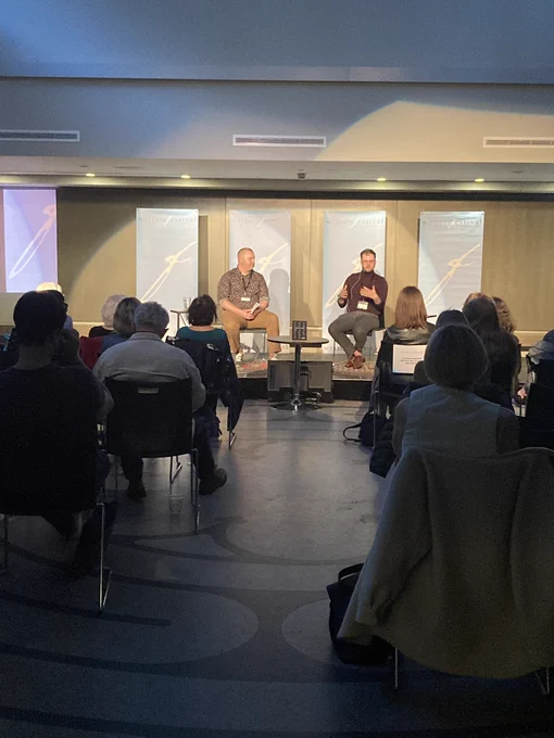 Martin Lee and Alex Manley sitting on the Ottawa Writers Festival Stage.