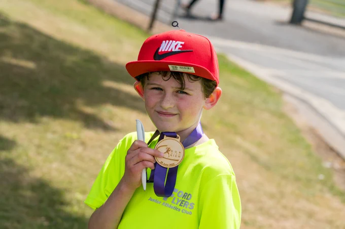 A young participant from Run with Rich 2022 proudly shows off his medal 