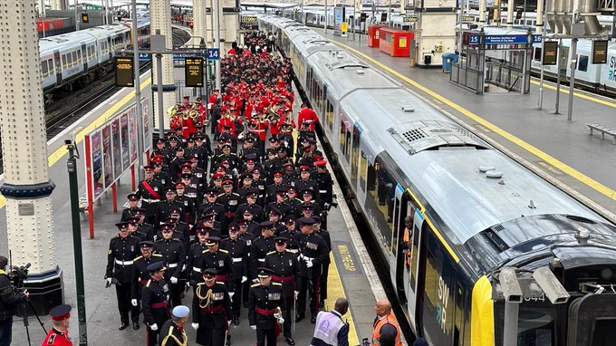 A platform at London Waterloo filled with arriving soldiers in dress uniform.