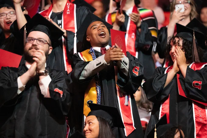 Photo of graduates standing up and cheering