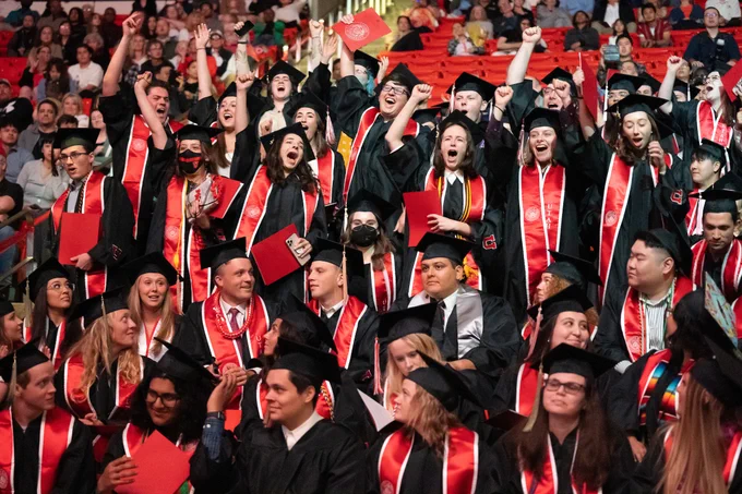 Photo of group of graduates standing up and cheering