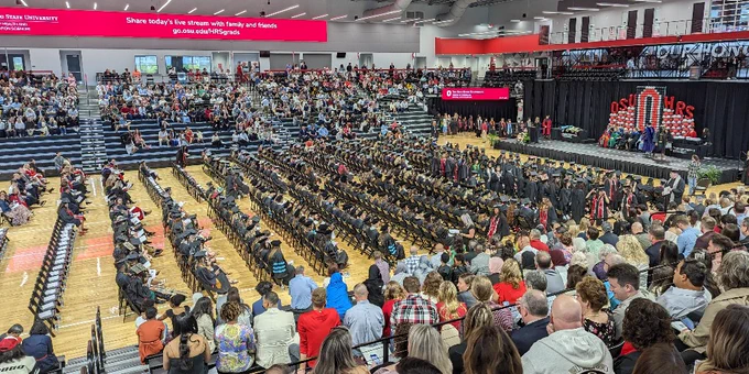 Graduates seated on the floor looking towards the stage.