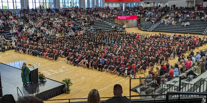 Graduates seated on the floor looking towards the stage.