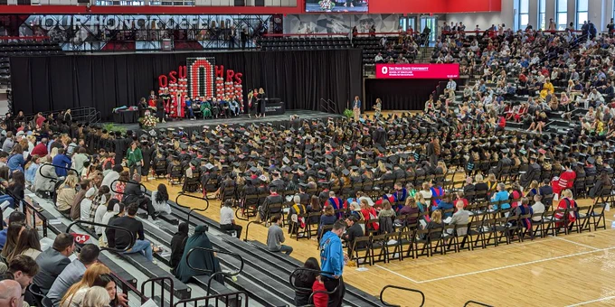 Graduates seated on the floor looking towards the stage.