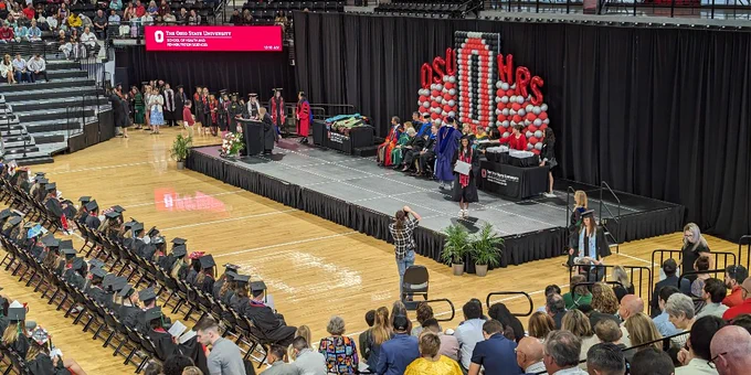 Graduates crossing the stage while receiving their certificates.