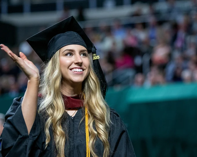 A graduate student smiles and waves