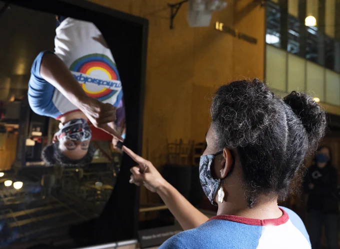 Dr. Desiré Whitmore, PhD pointing at her reflection from the Exploratorium’s Giant Mirror