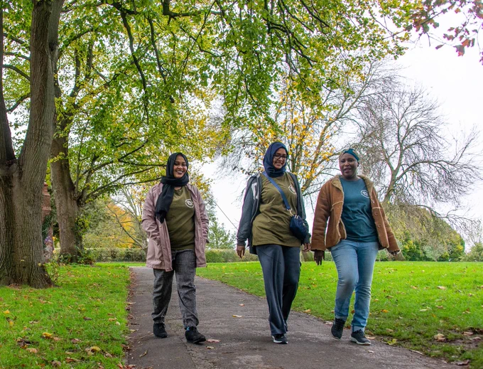 Three women walking through a park.