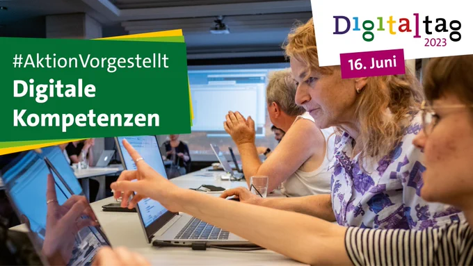 Menschen sitzen in einem Seminarraum. Eine Frau schaut auf einen Laptop-Bildschirm. Die Frau neben ihr zeigt mit dem Finger auf den Bildschirm. Links steht auf einem Textfächer: "#AktionVorgestellt Digitale Kompetenzen"; rechts oben steht das Digitaltag-2023-Logo und das Datum 16. Juni
