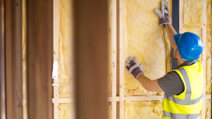 Photo of a workman fitting insulation into a wall.