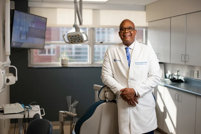 Photo of Dr. Richardson in white coat standing behind dentist chair