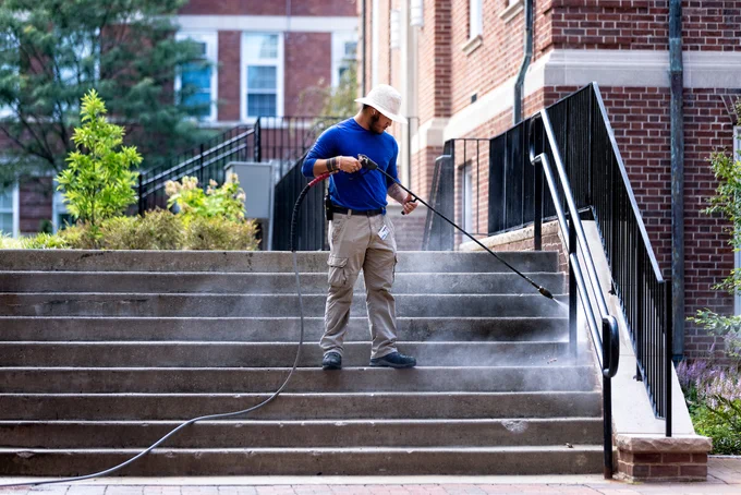 Photo of staff member pressure washing concrete