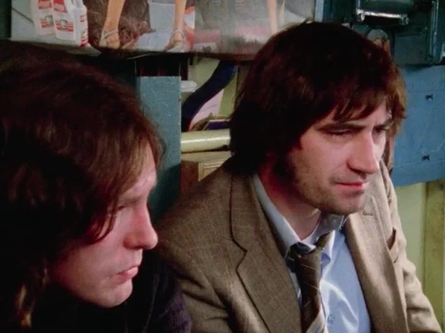 Two long haired white men in conversation, in a still from Just a Boy’s Game