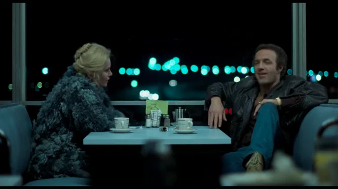 A man and a woman sit in a diner booth, in a still from the Michael Mann film Thief.