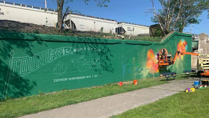 Artist Thomas “Detour” Evans working on a mural at Foundry Field in South Bend.