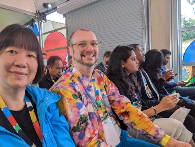 Margaret takes a selfie next to developers sitting in a row.