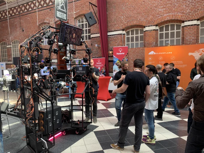 People gathered around a rig setup at Nordic Game. They are stationed in front of Cloudflare and Thunderful's booths.