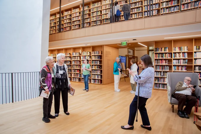 Dean of Libraries Susan Fliss takes a photo of two visitors standing in front of the oculus inside Neilson Library