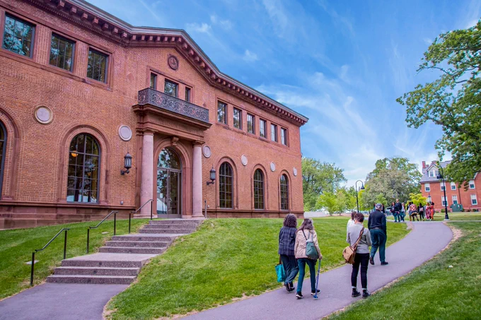 Exterior shot of Neilson Library with small groups of visitors walking past on a paved path