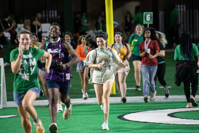 Students running on the football field.