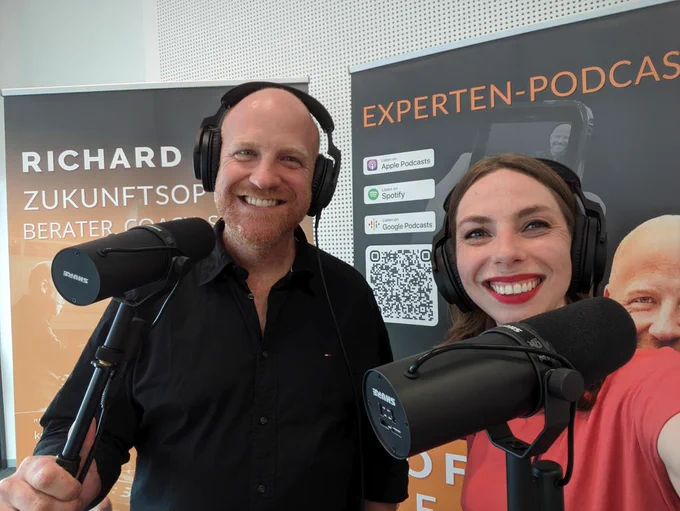 Richard and me with headphones and microphones in front of banners for his podcast 