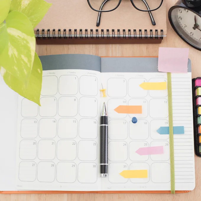 An open planner on a desk with a pen  