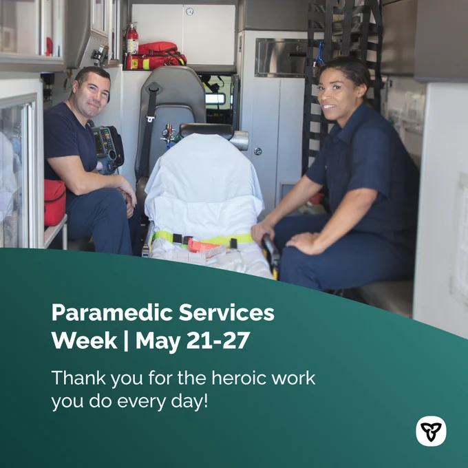 Two paramedics seated in the back of an ambulance. Image Text: Paramedic Services Week | May 21-27. Thank you for the heroic work you do every day!