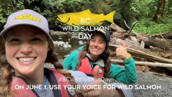 Two women standing in front of a creek giving the thumbs up for BC Wild Salmon Day.