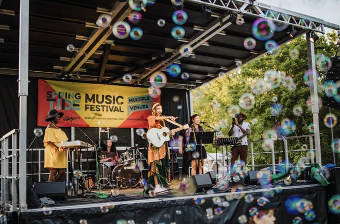 Band playing on stage with bubbles flying in the air at Springtide Music Festival in Uxbridge