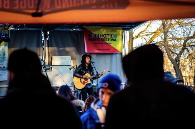 Man playing the acoustic guitar on an outdoor stage in front of a crowd at Springtide Music Festival in Uxbridge