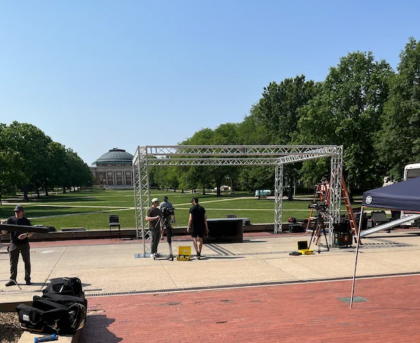 PBS NewsHour production team setting up equipment at Anniversary Plaza