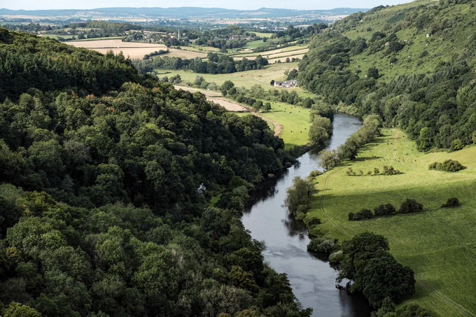 Green fields and wooded landscape with the River Wye running through it.