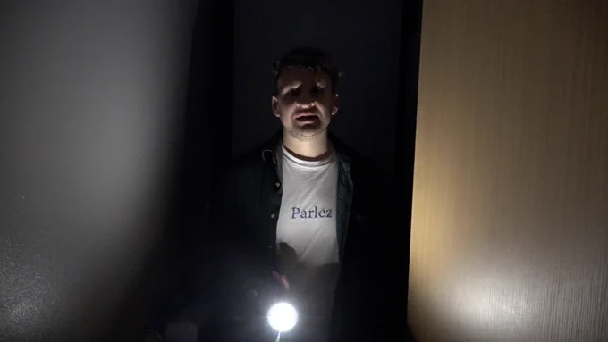 Daf holds a torch in a dark room.