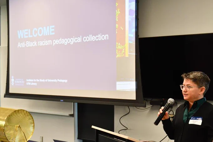 Professor Ruth Childs, director of the Institute for the Study of University Pedagogy (ISUP), stands at the podium holding a microphone, introducing the Anti-Black Racism pedagogical collection, a collaboration with ISUP and the UTM Library. 