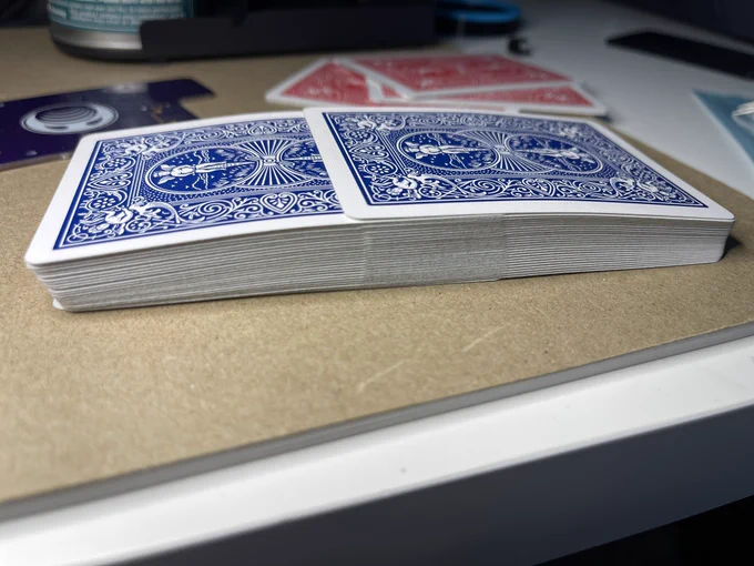 A deck of cards mid-shuffle laying on a desk. The two halves of the deck are perfectly interwoven with every other card belonging to each half.