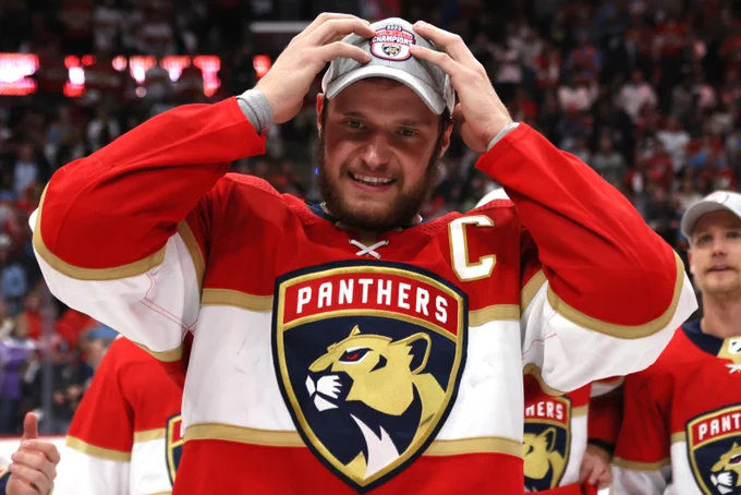 Aleksander Barkov on ice in a Florida Panthers home uniform with his hands over his head after being crowned the Eastern Conference champions