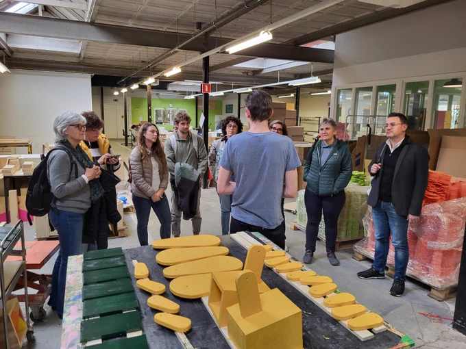 El grup participant al projecte està escoltant l'explicació d'un dels responsables d'una iniciativa que treballen amb la fusta. 