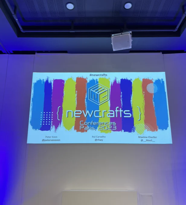 Premier slide de la keynote d’ouverture de newCrafts Paris 2023 : fond de barres verticales de 5 couleurs différentes (turquoise, bleu foncé, violet, jaune, orange), et par-dessus le logo de NewsCrafts