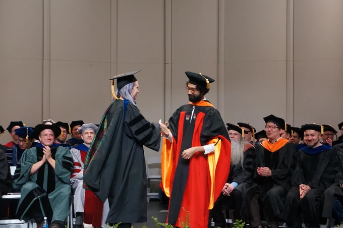 Chinmay and I shaking hands on stage during my graduation ceremony
