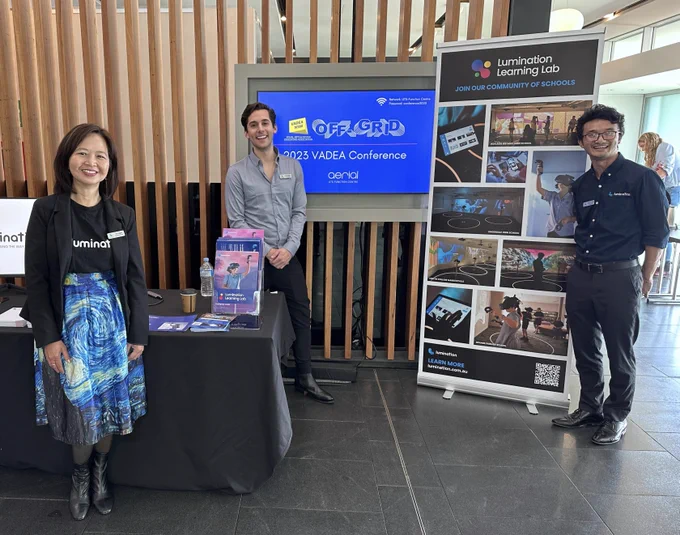 Three people stand in front of sign that reads 2023 VADEA Conference and next to Lumination Learning Lab pull-up banner showcasing different Lumination products 