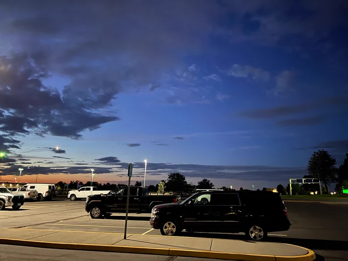 Photo of a parking lot with crescent moon before sunrise