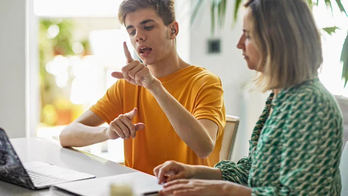 Person sitting alongside a teenager using sign language