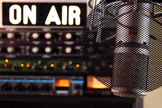 Photograph of a microphone and background text "On air"