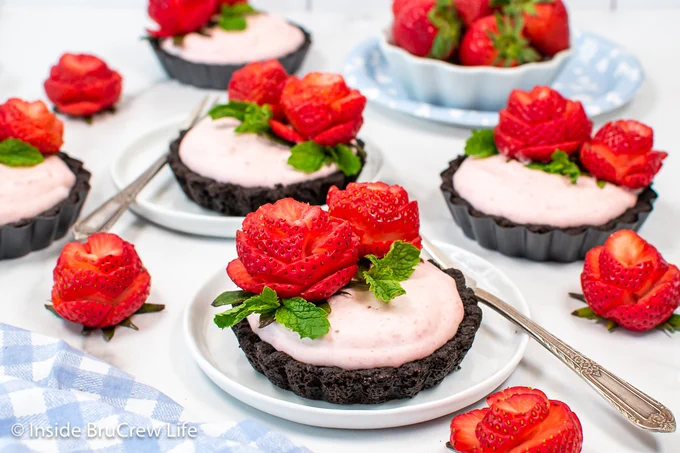Mini pies with Oreo crust, fluffy filling, and fresh strawberries on white plates.