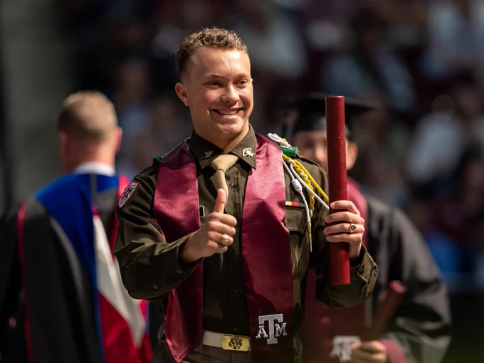 A graduate gigging 'em and smiling after getting his diploma on stage.
