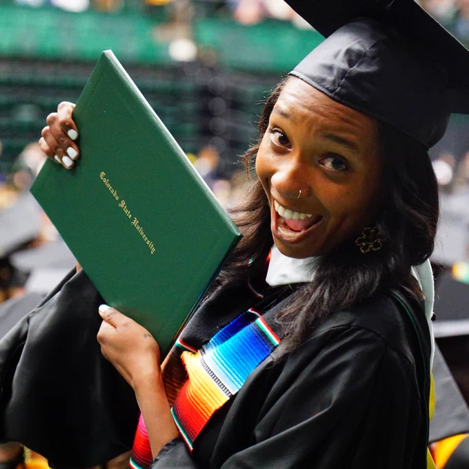A graduate smiles while holding her degree.